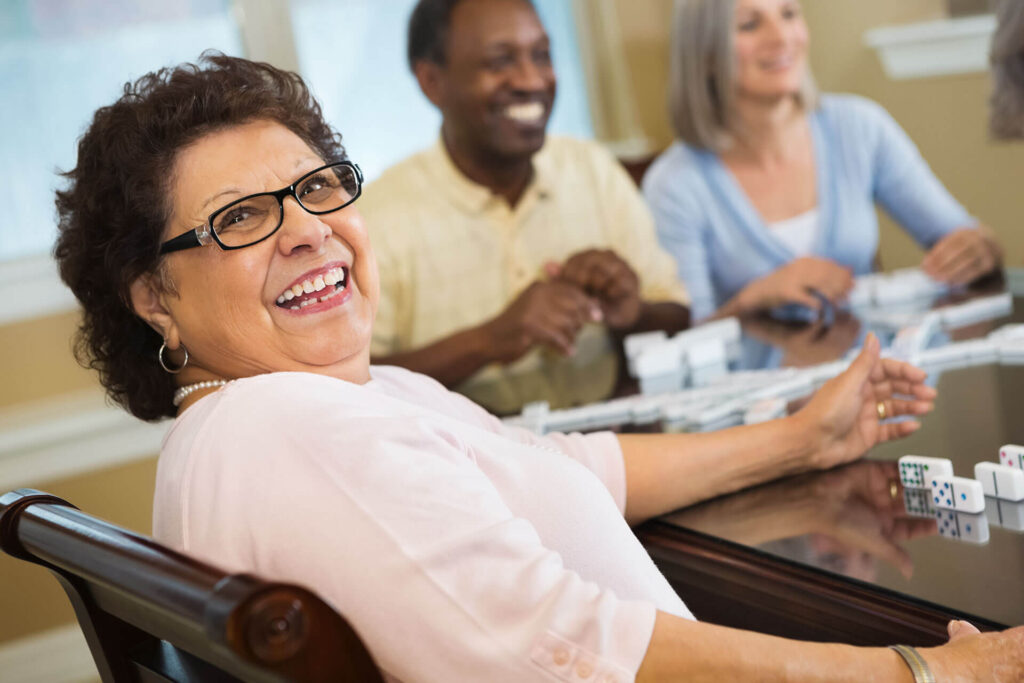 A senior woman plays dominoes with friends.