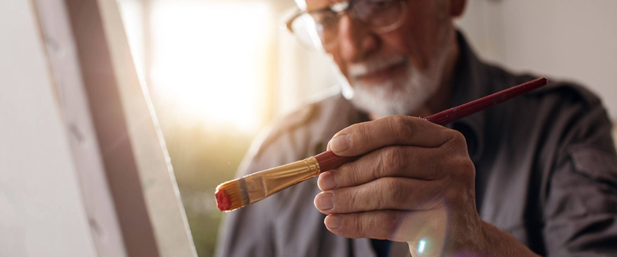 A close up of a senior man painting on a canvas