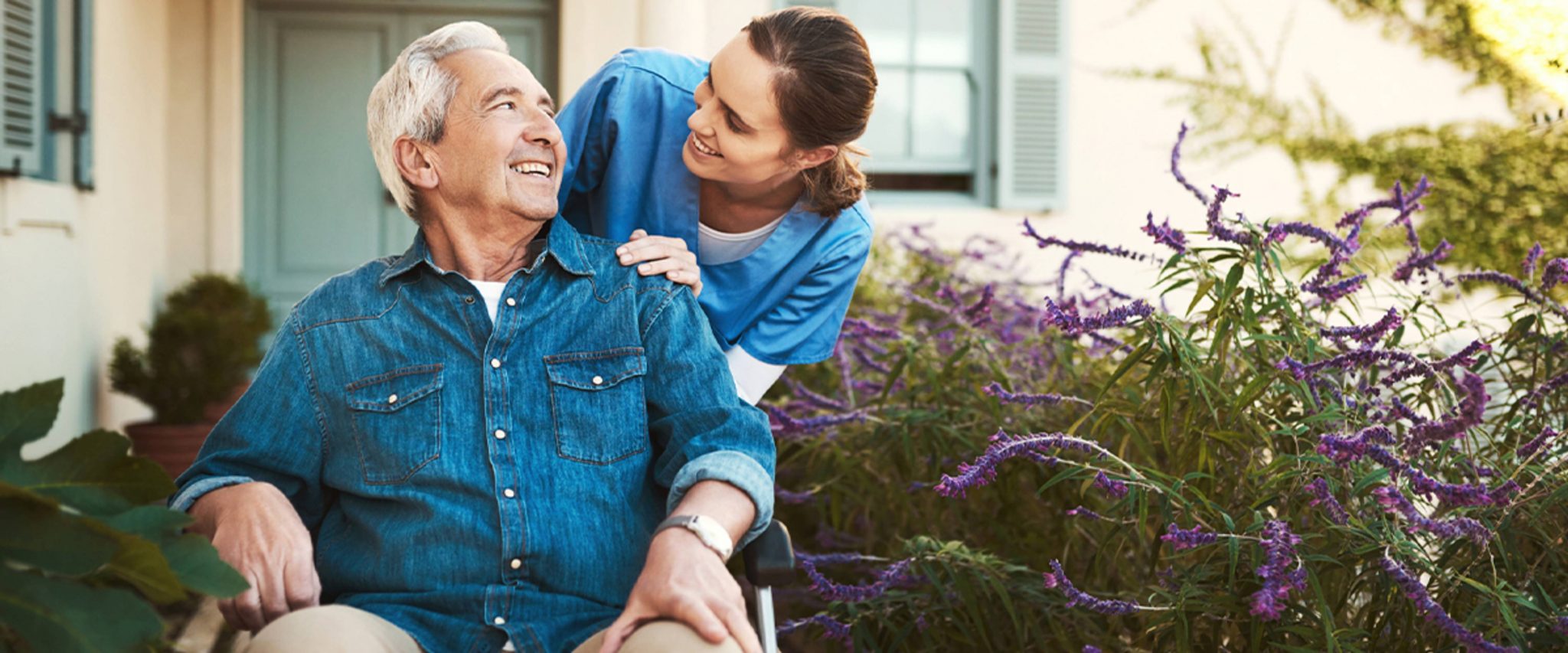 healthcare professional taking an elderly man in a wheelchair on a walk