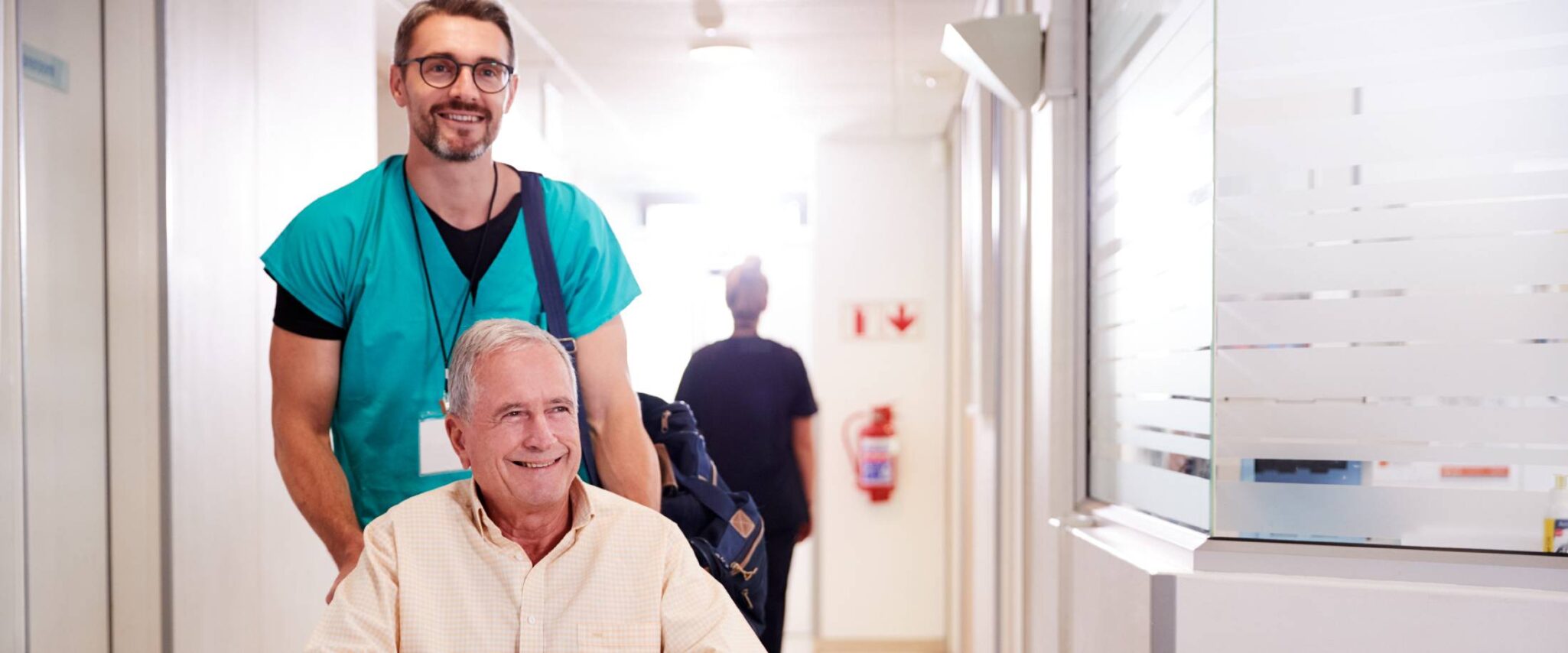 senior being pushed in a wheelchair by healthcare worker