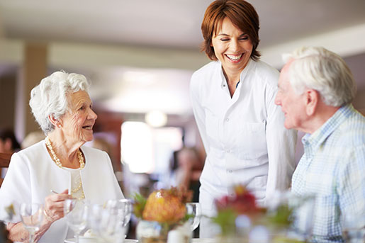 A senior couple enjoy a meal in a formally decorated dining room.