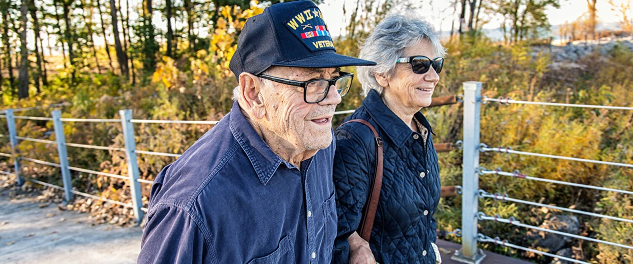 An elderly veteran walks in the forest with his spouse