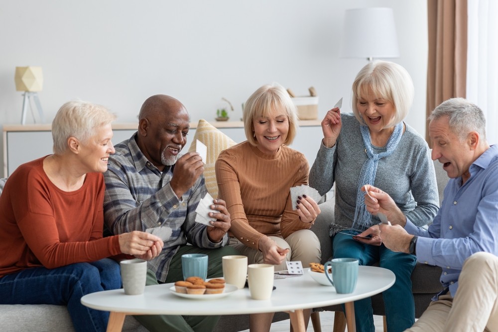 Group of happy senior friends in casual setting playing cards