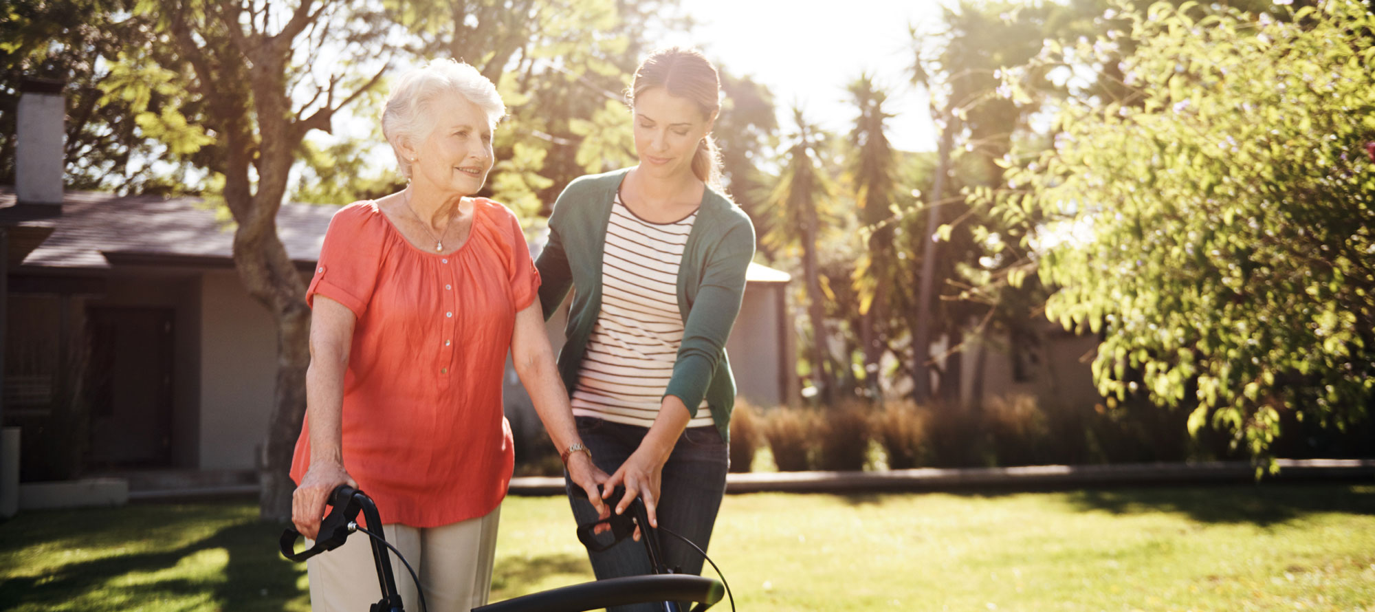 Woman helping her elderly mother walk outside