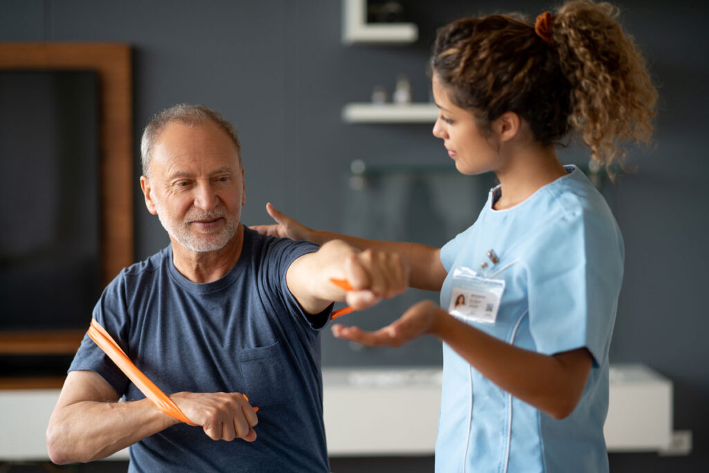 A senior man exercises with bands with a physical therapist.