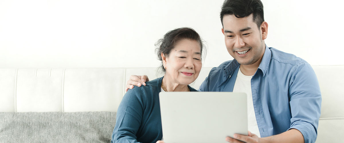 Senior woman with her son looking and smiling at a tablet