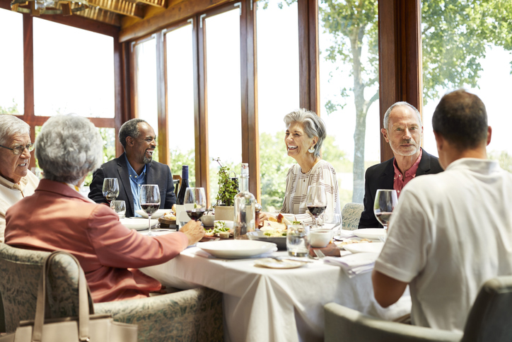 group of older retired adults enjoying a meal together at a retirement community