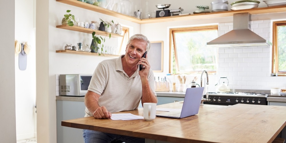 senior man talking on his phone and using a laptop