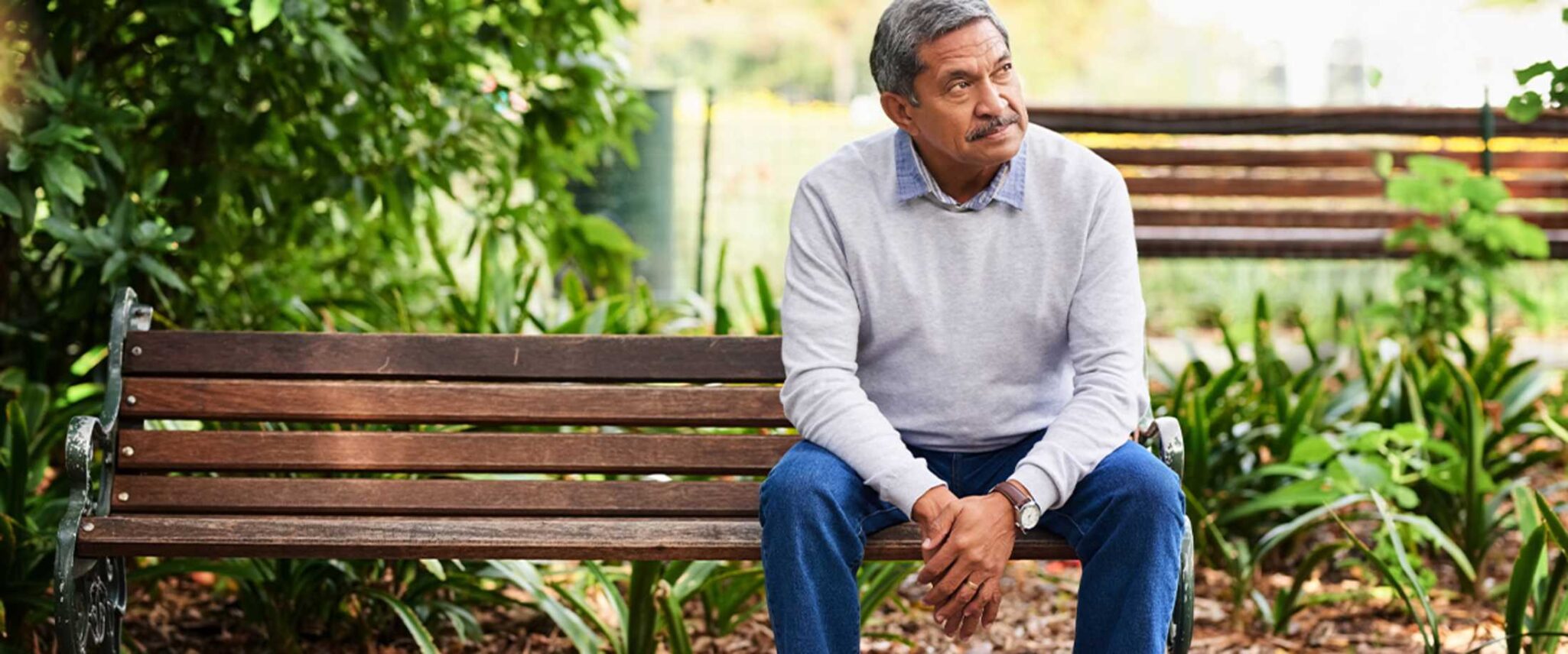 senior man sitting on a bench outside his retirement community