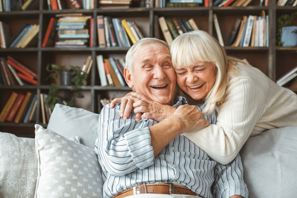 Senior couple hugging in a decorated apartment.