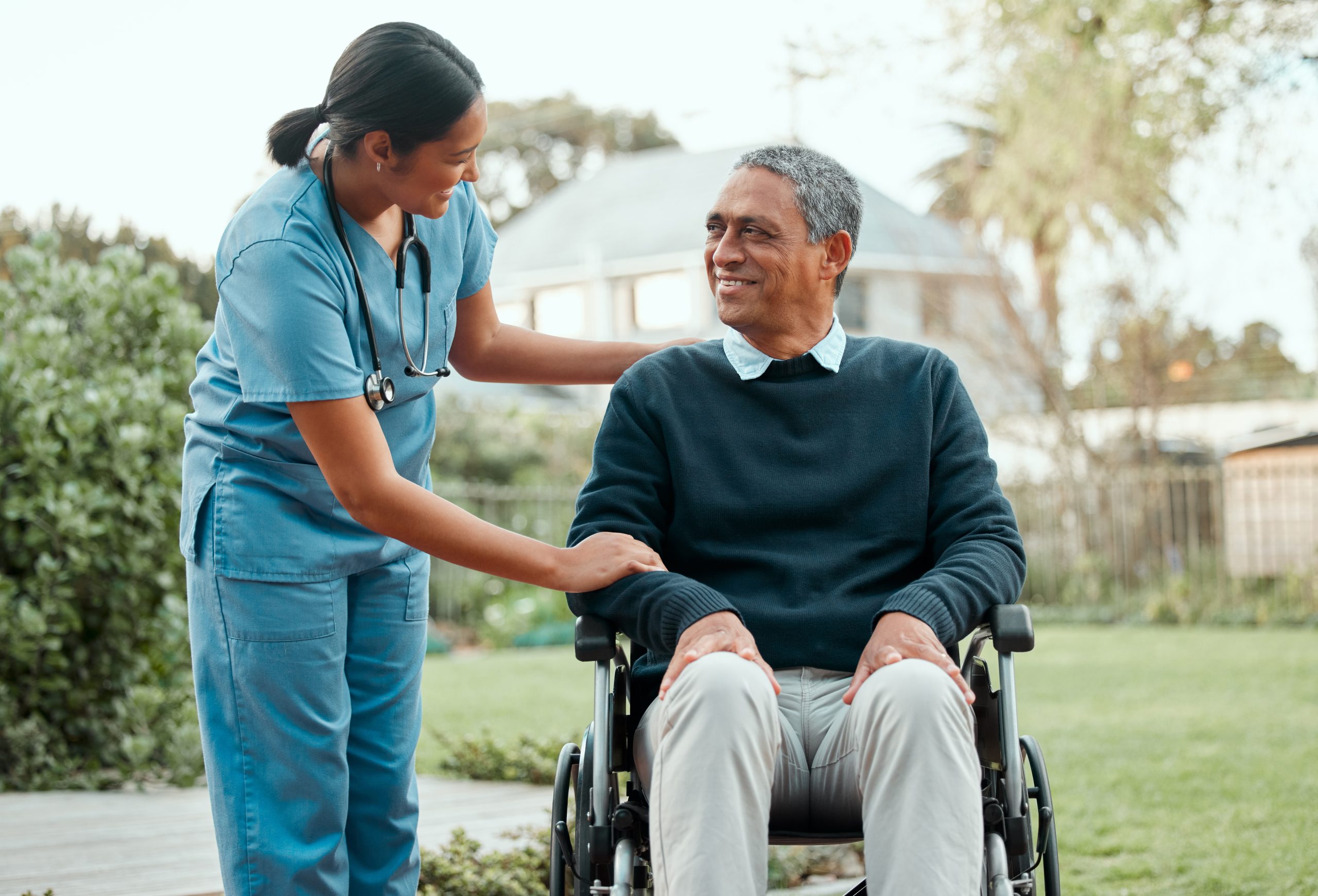 Senior man in wheelchair smiling at female nurse