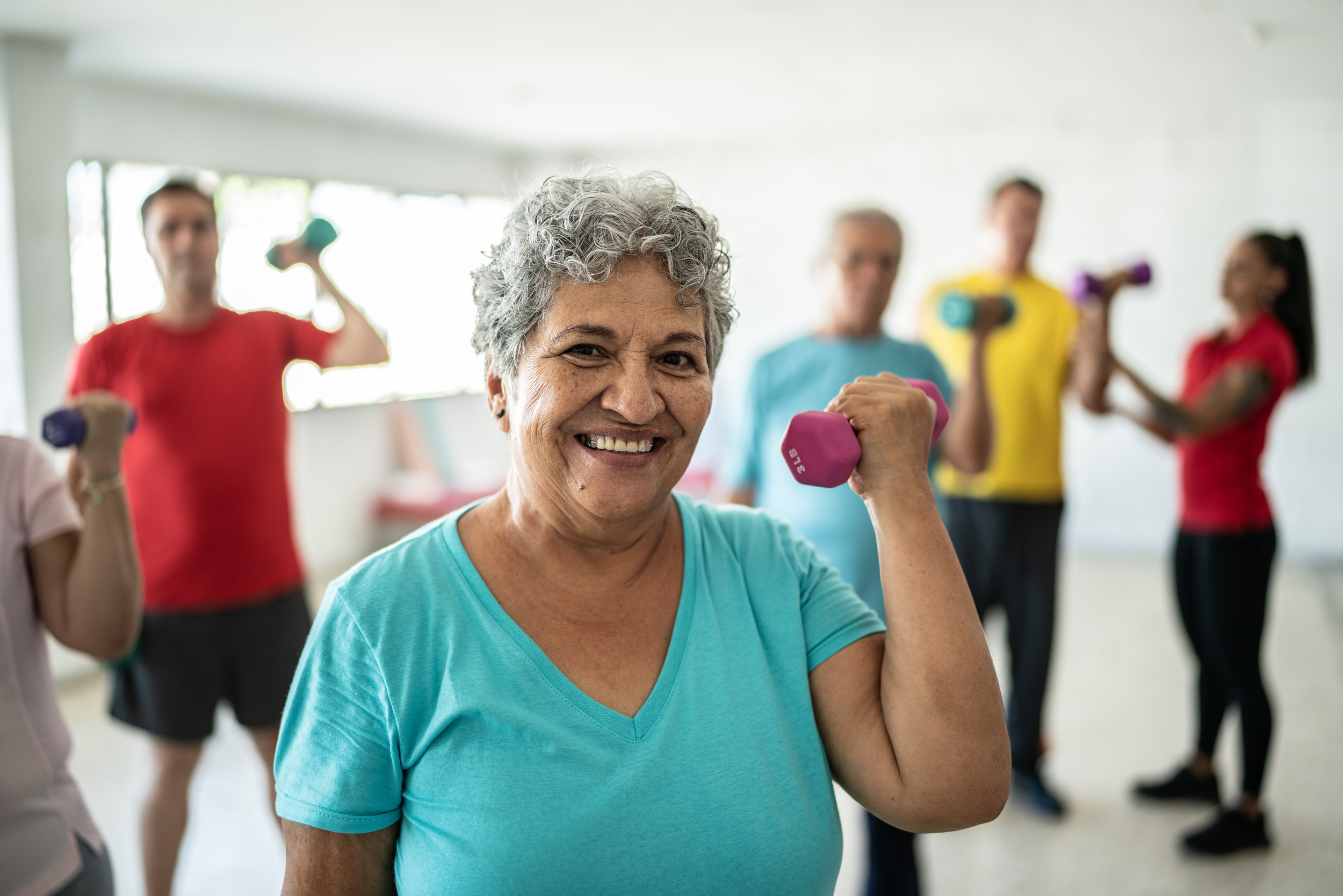 Senior woman in fitness class holding up dumbbell
