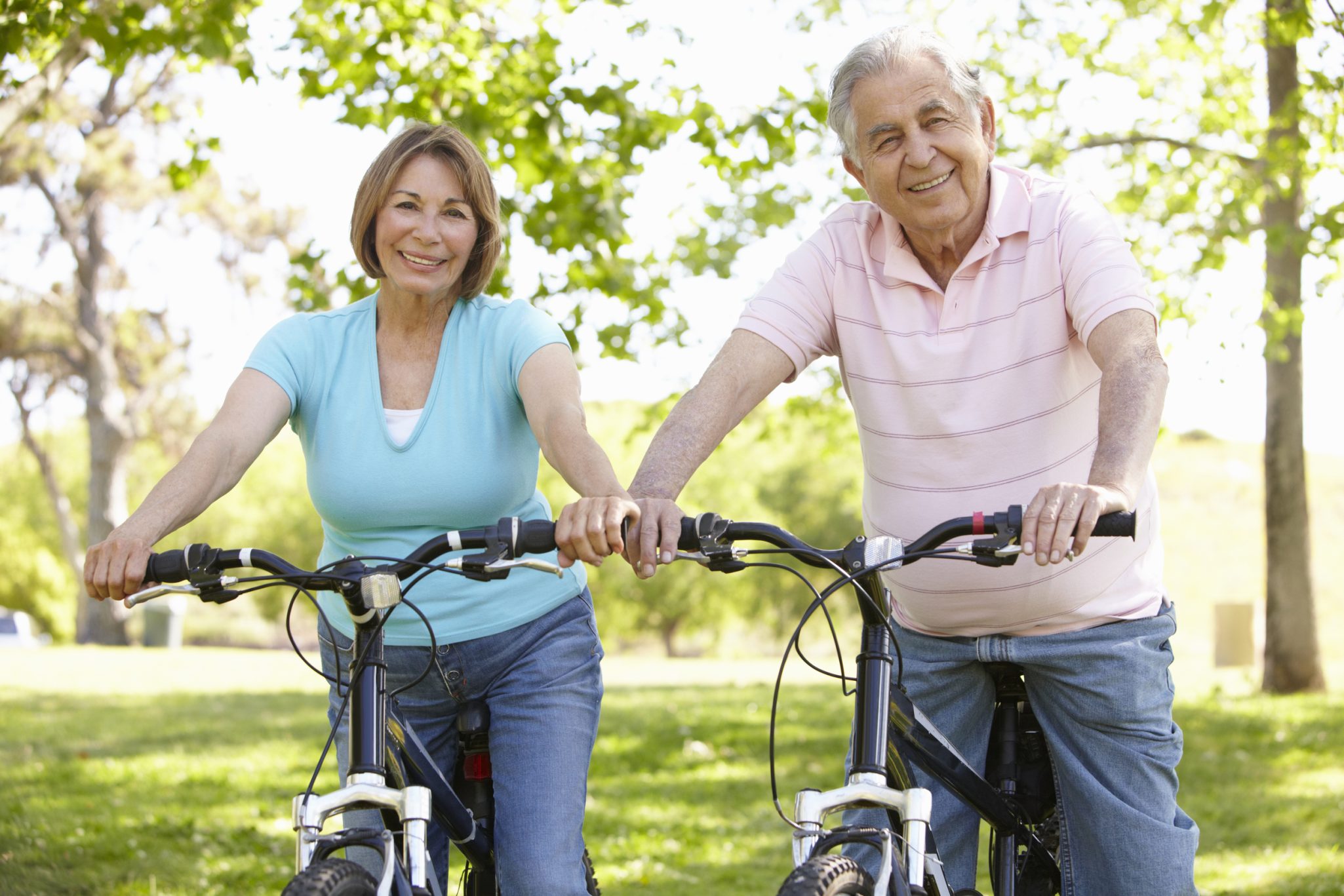 Senior couple sitting on bikes in a park