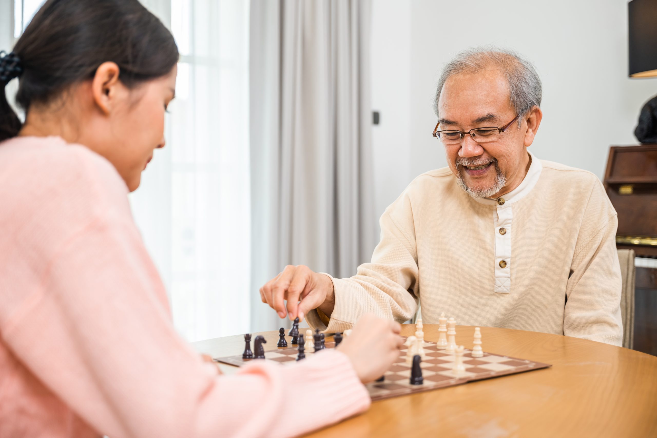 Senior man playing a game of chess with adult daughter
