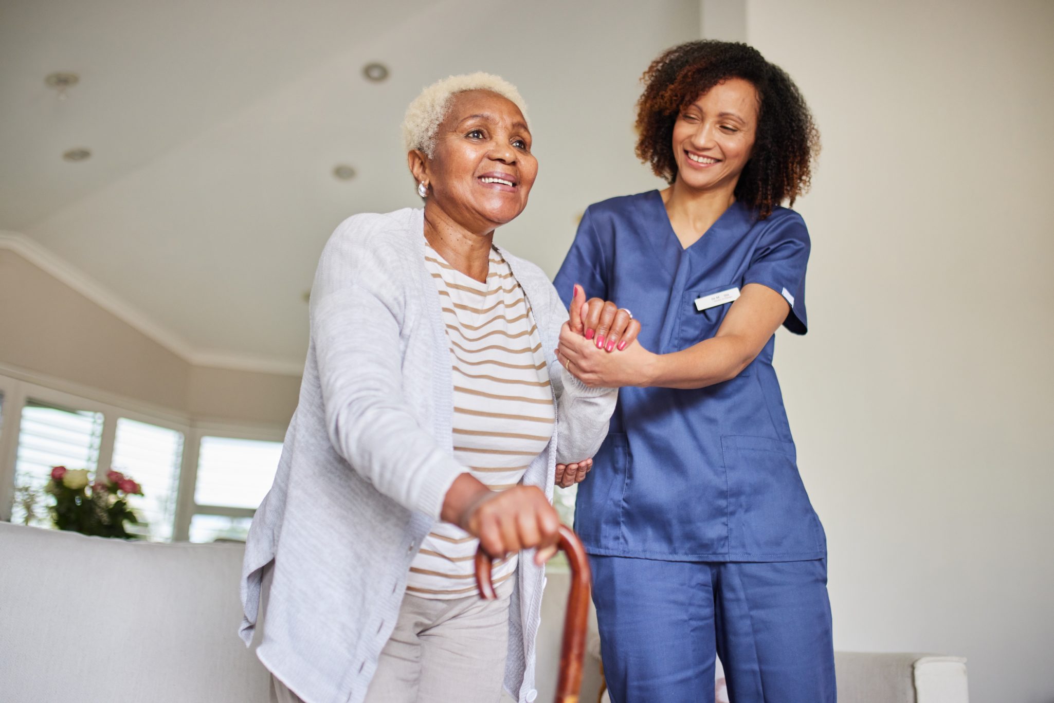 Female nurse assisting senior woman with a cane