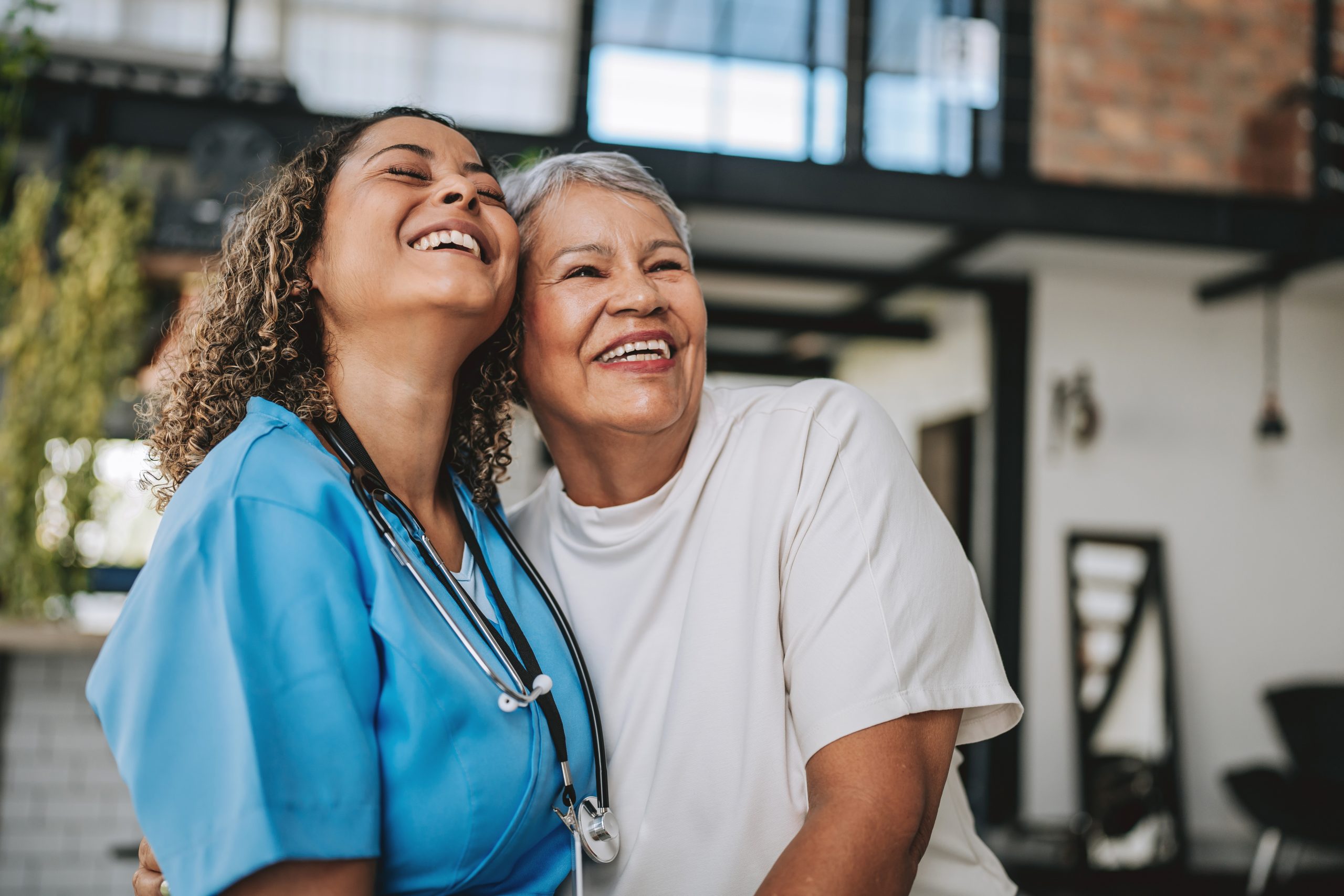 Senior woman smiling and hugging female healthcare worker