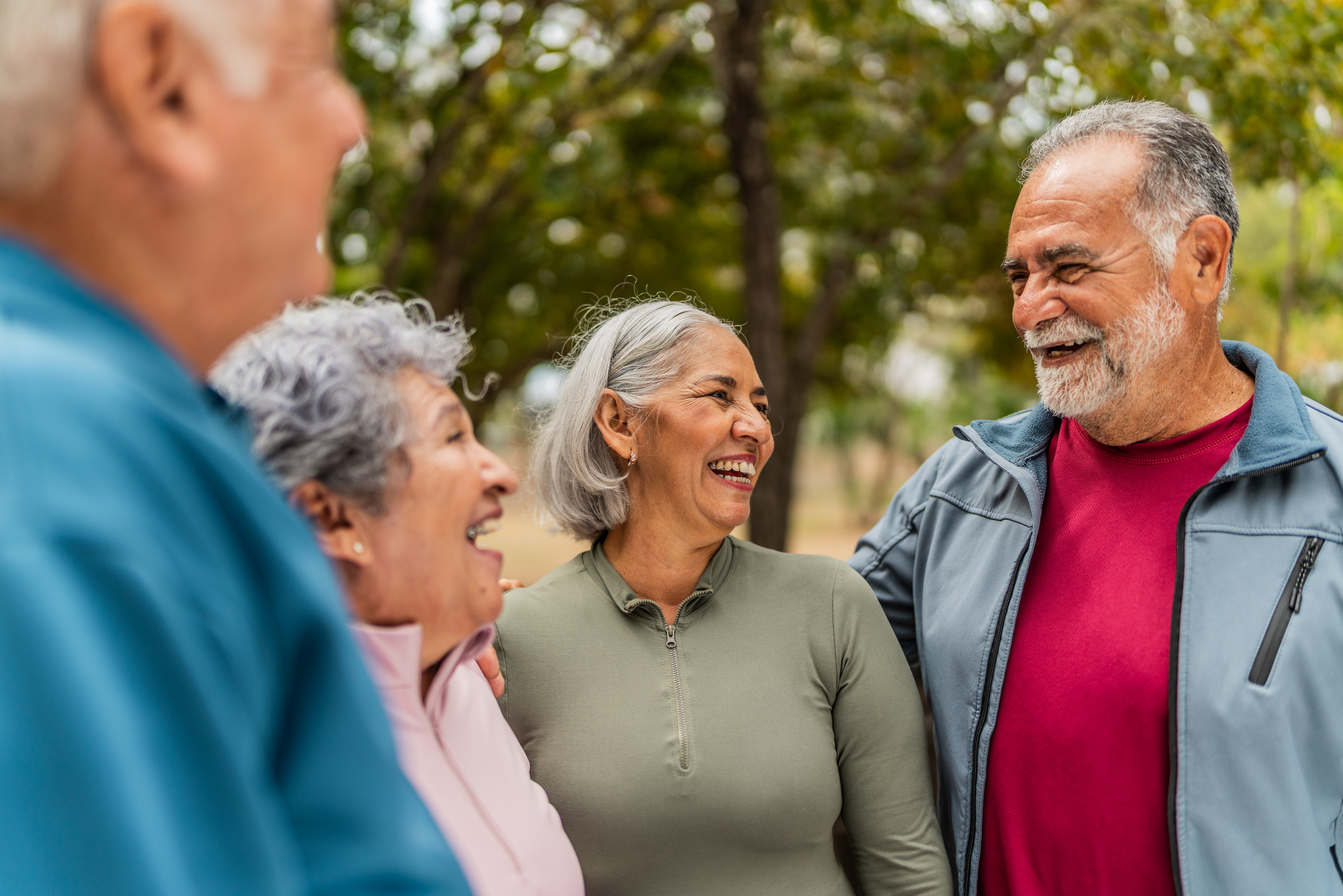Group of older adults standing outdoors, smiling and laughing together